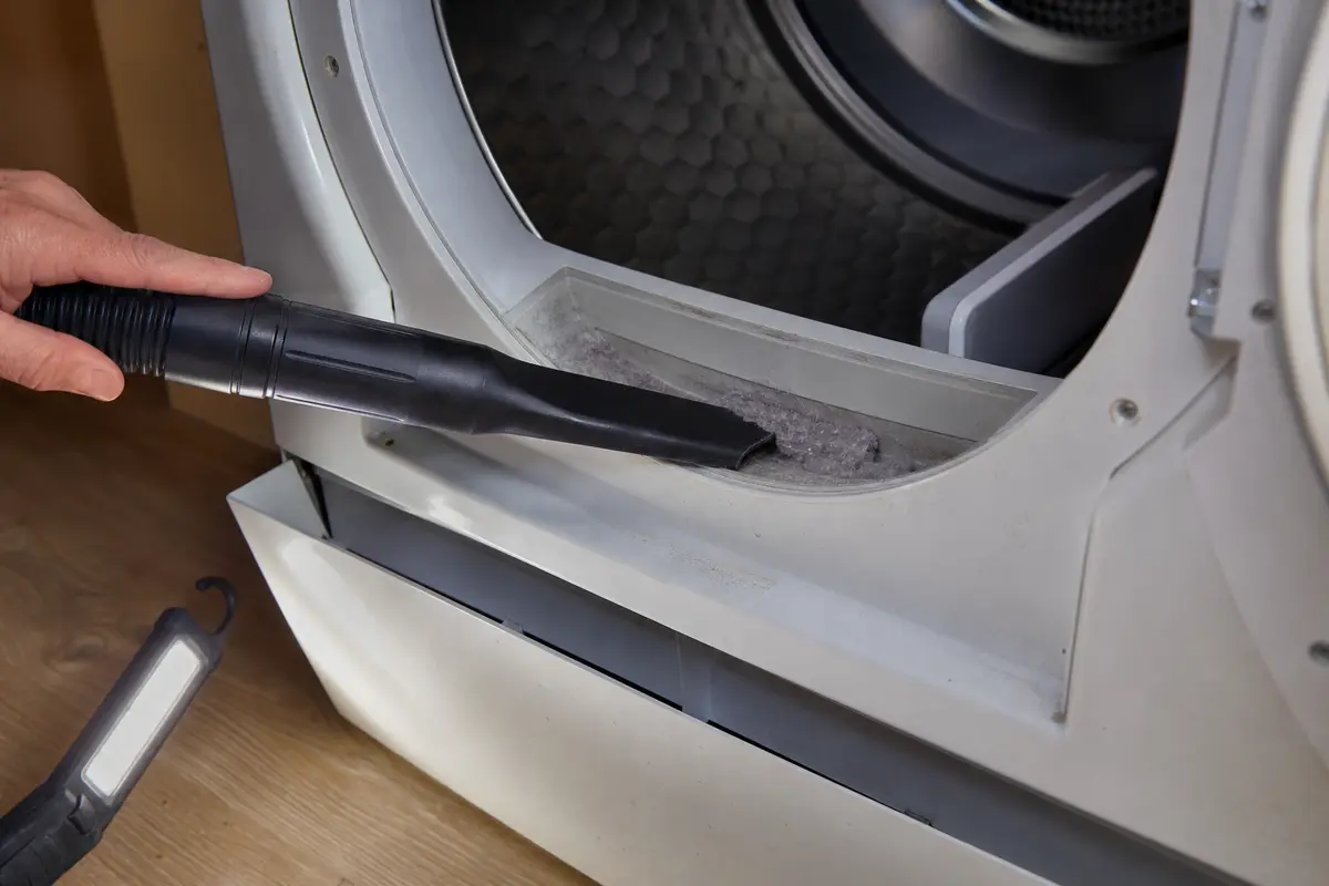 Vacuum crevice attachment cleaning lint from a Miele-style dryer filter slot