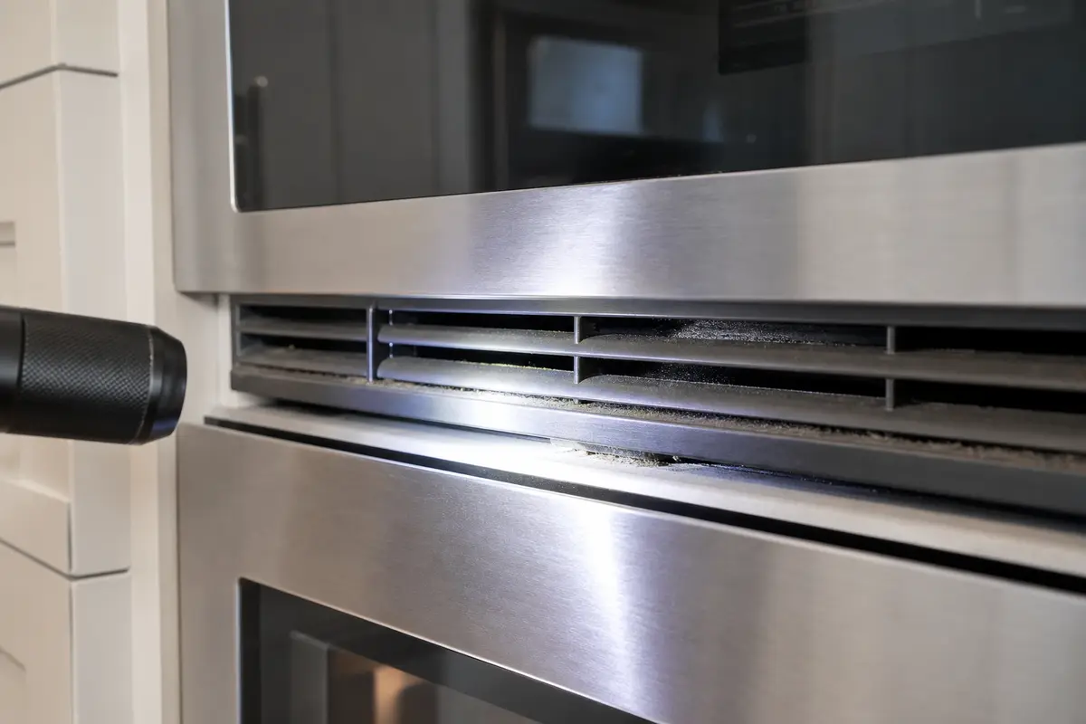 Close view of built-in oven cooling vent slots checked with a flashlight