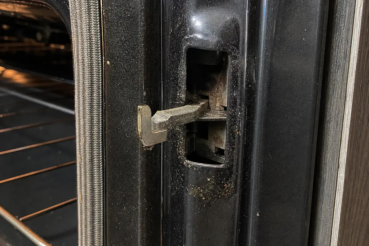 GE Profile style oven latch sitting halfway in the door lock opening