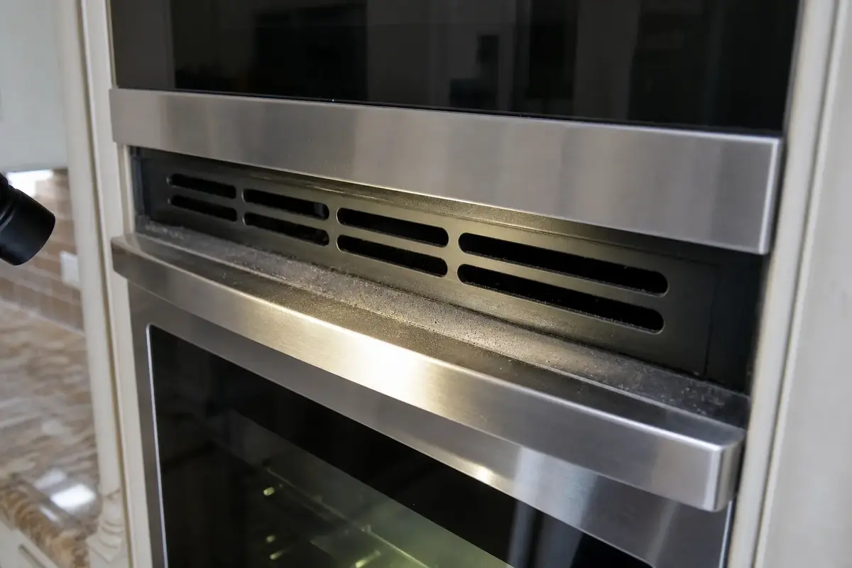 Close view of GE Profile style oven cooling vent slots with dust and grease buildup