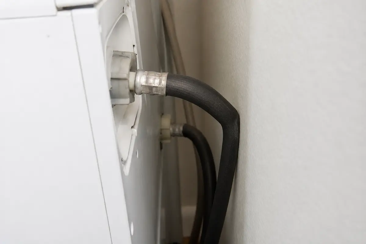 Washer fill hose forced into a restrictive bend between the cabinet and wall