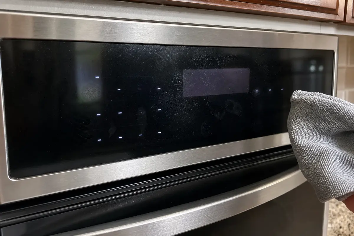 Samsung style oven touch panel with residue and a dry microfiber cloth nearby