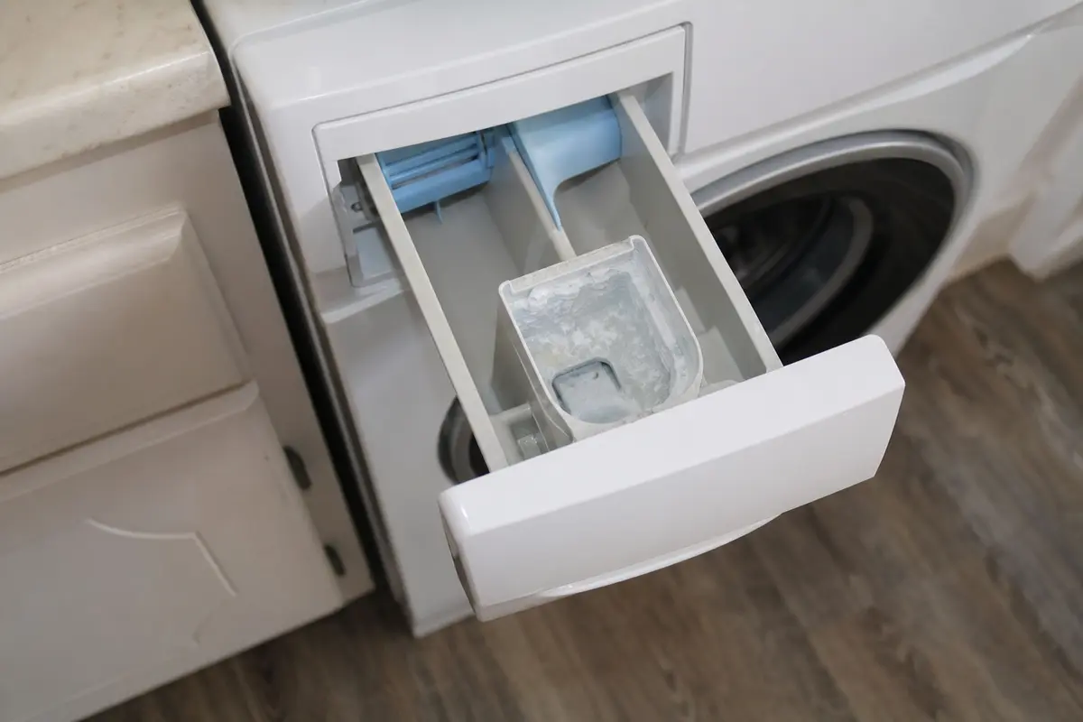 Washer dispenser drawer pulled open with cloudy residue in the fabric softener cup