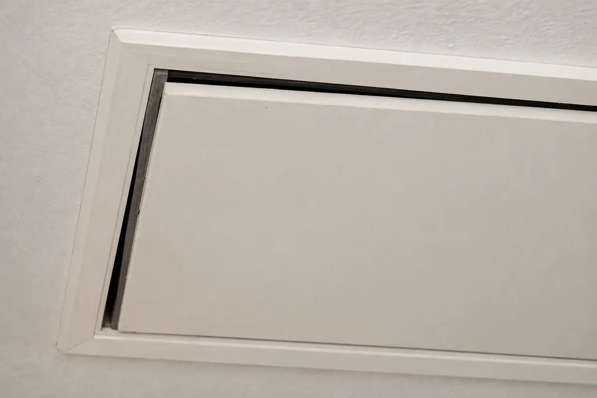 Uneven attic hatch gap showing a missing compression seal at the ceiling frame