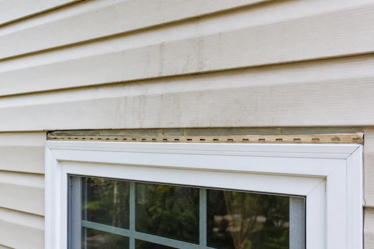 Exterior window and siding checked above the trim for a flashing leak