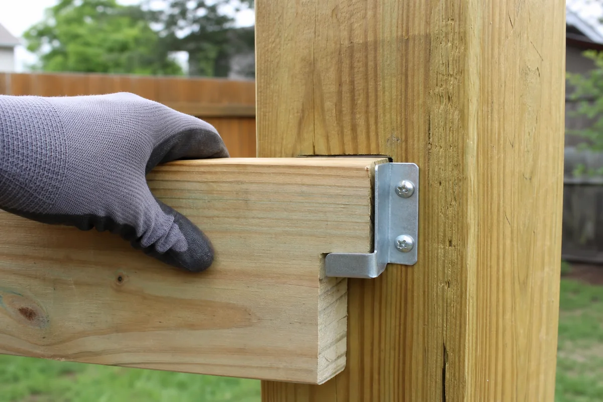 Exterior fence rail bracket supporting a new horizontal rail at a sound wood post