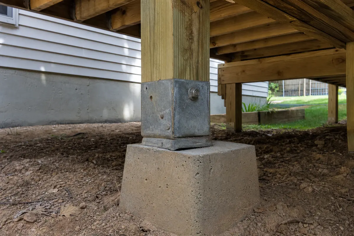 Deck post base on a concrete pier checked from below for wobble clues