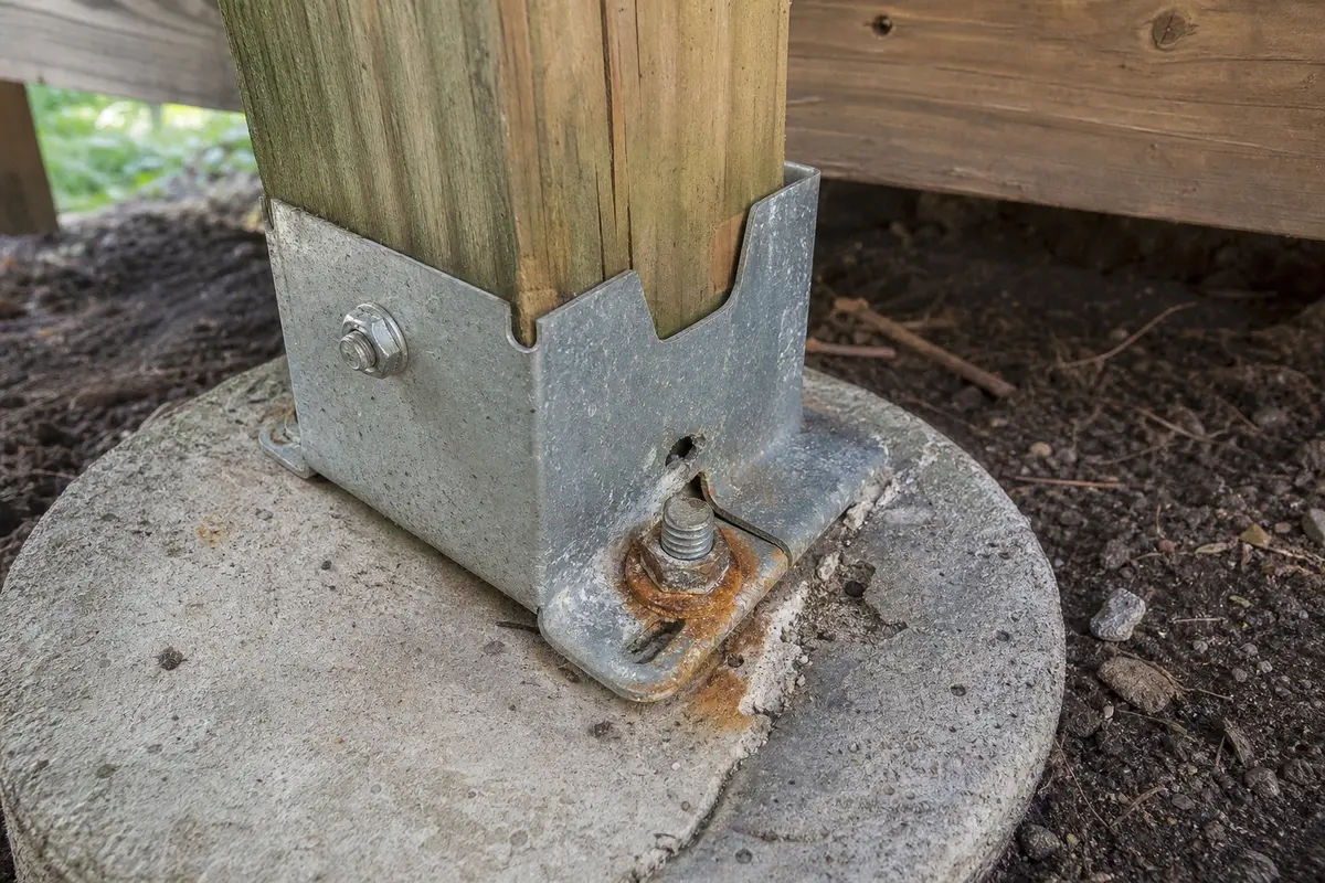 Close view of loose deck post base anchor hardware and rust staining