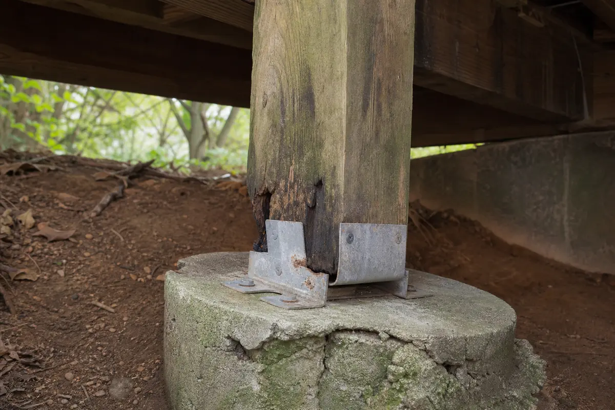Rotted deck post bottom and damaged concrete at a post base