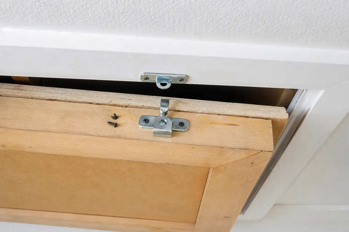 Attic hatch latch aligned to pull an access panel tight