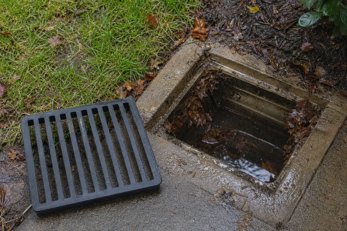 Replacement catch basin grate beside an open yard drain basin