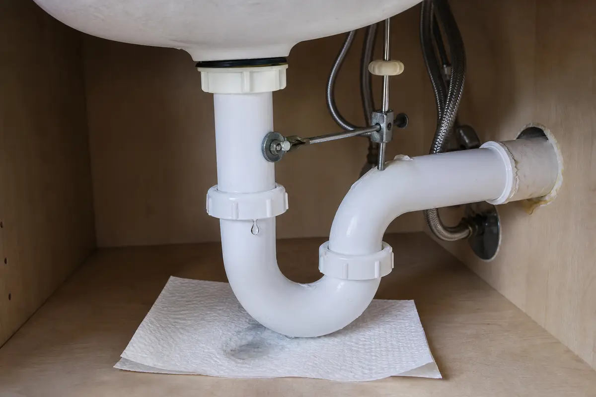 Bathroom sink P-trap slip joint dripping onto a dry paper towel during a drain test