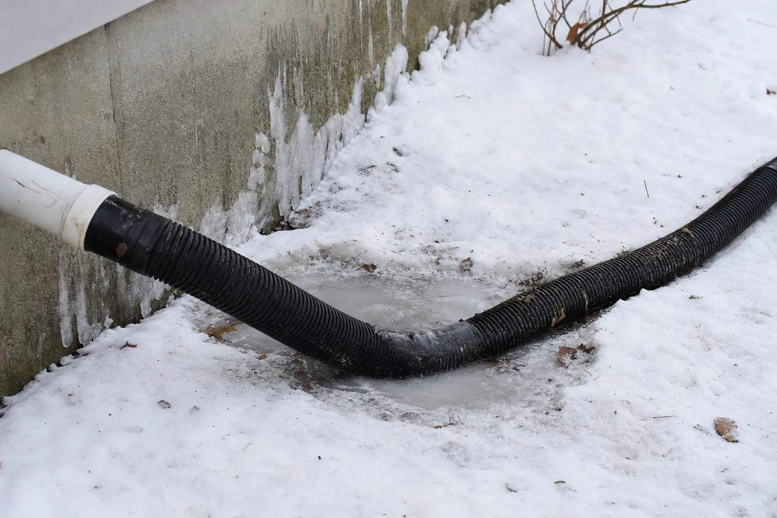 Sagging sump pump discharge extension holding frozen water in a low spot