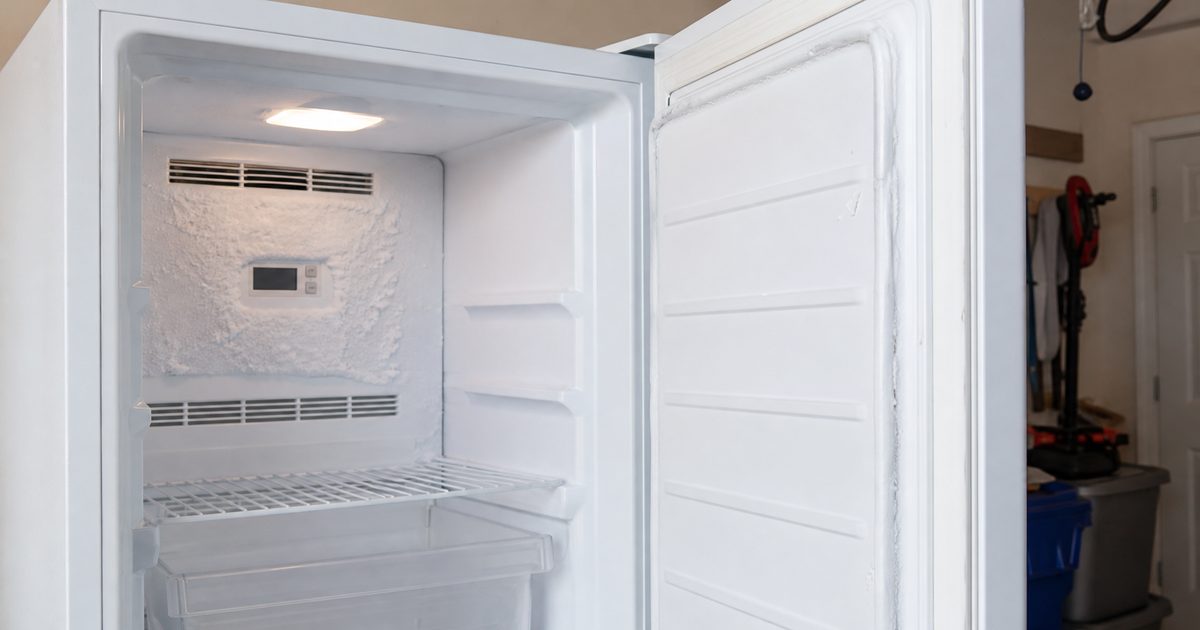 Open upright freezer with frost buildup around the rear interior vent area