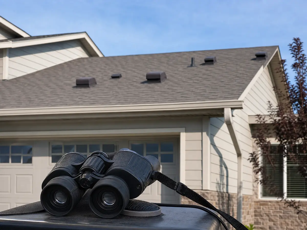 Inspection binoculars used to check a roof ridge vent from the ground
