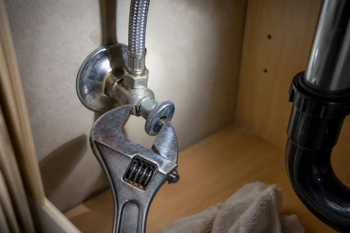 Adjustable wrench on bathroom sink shutoff plumbing