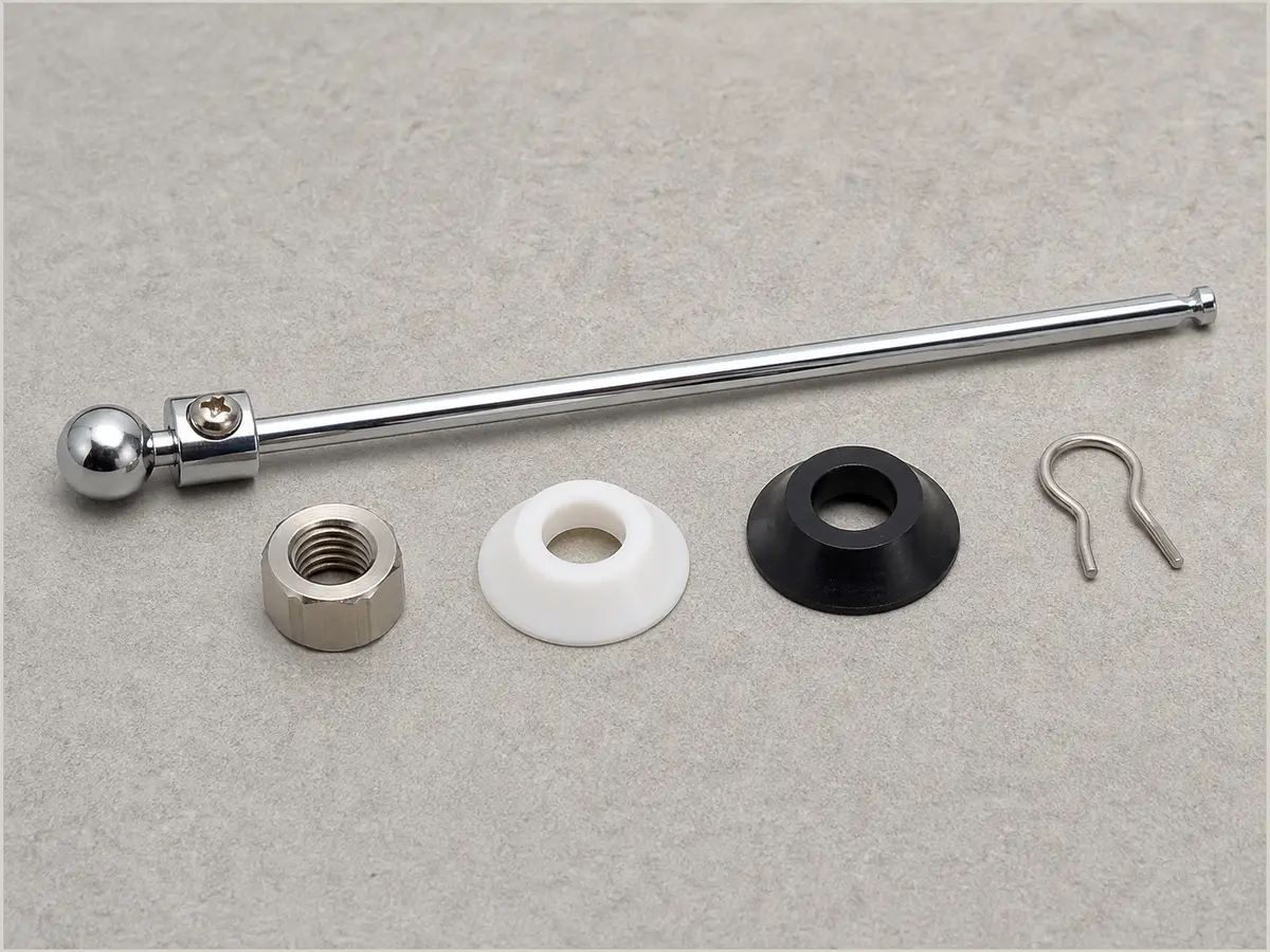 Bathroom sink pop-up pivot rod, ball seals, retaining nut, and linkage clip laid out for comparison