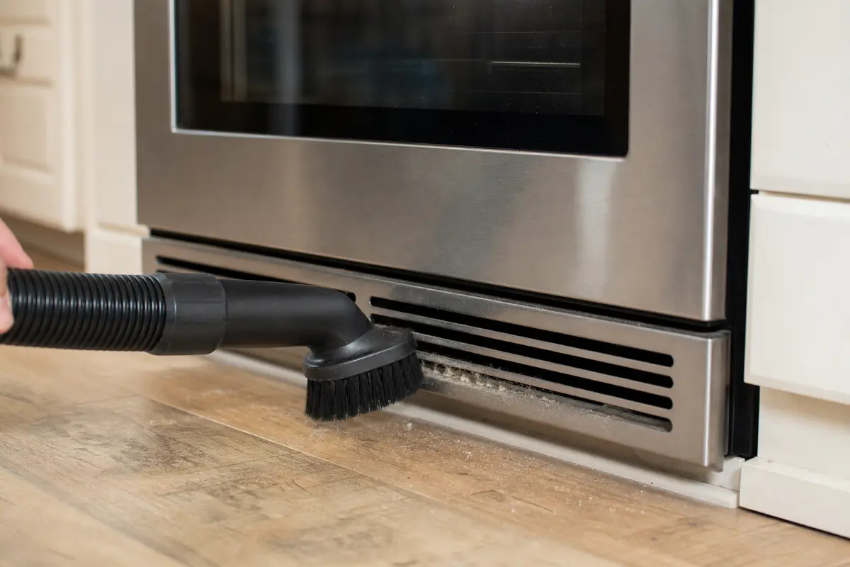 Vacuum brush attachment for cleaning oven vent slots from the outside