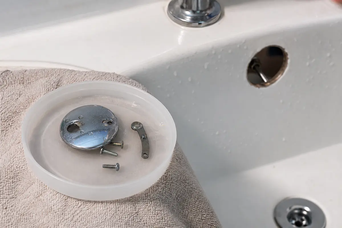 Small tray catching overflow plate screws beside the tub drain